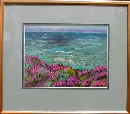 The blue green ocean of the San Simeon Coast, with white capes in the water on in the foreground the plants are blooming in vibrant pinks and yellows.